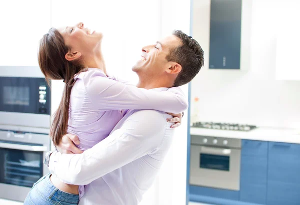 Young happy couple in love hug in home kitchen