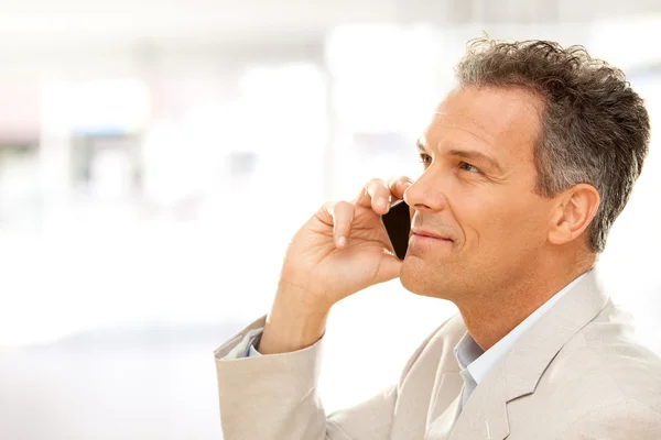 Handsome smiling businessman talk on phone at office