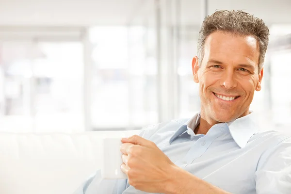 Handsome smiling businessman drink cup of tea at office
