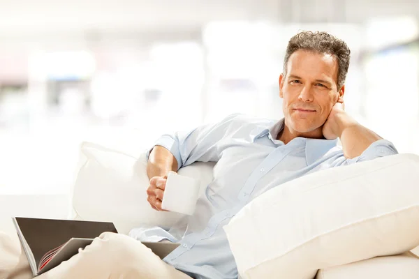Handsome businessman read and drink cup of tea on the couch at home