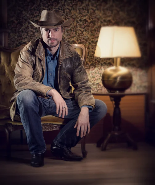 Handsome cowboy with sensual gaze and hat in a old house