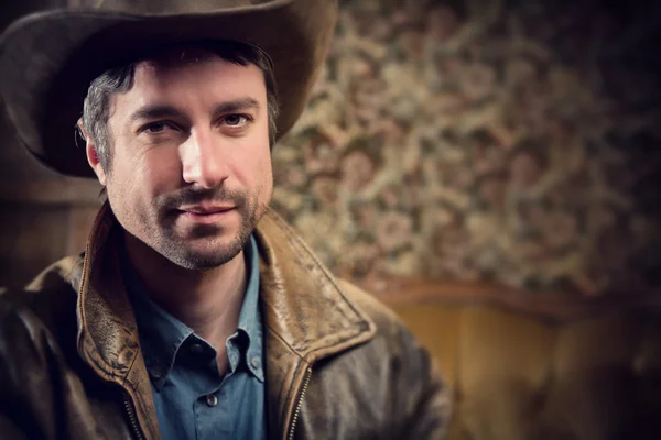 Handsome cowboy with sensual gaze and hat in a old house