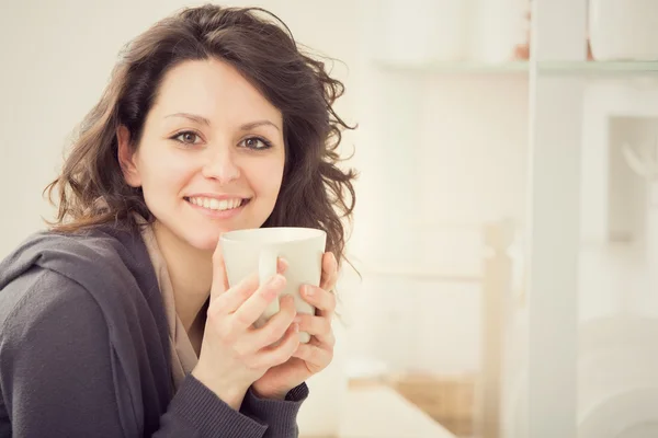 Young smiling girl with cup of tea in the kitchen