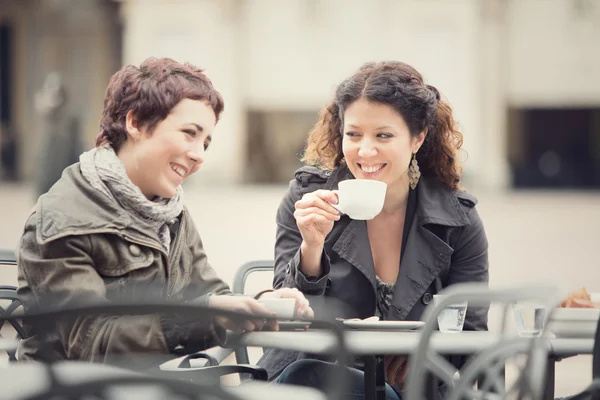 Couple of women have a coffee together in cityscape