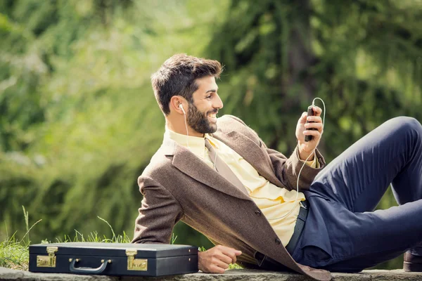 Young business man relaxing using smartphone outdoor in nature