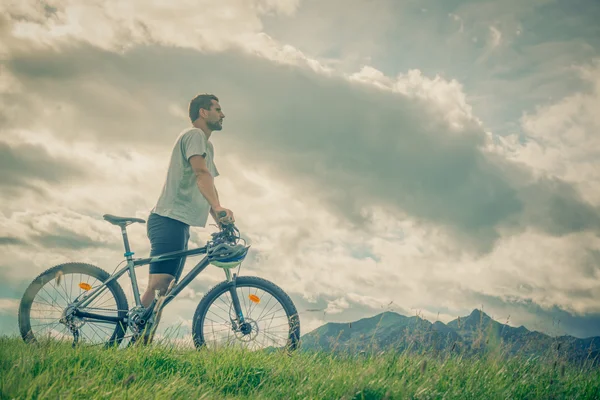 Young man stand near bike on mountain outdoor