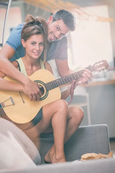 Young couple playing guitar on couch indoor