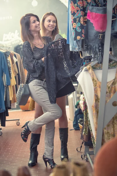 Two smiling friends enjoy in clothing shop