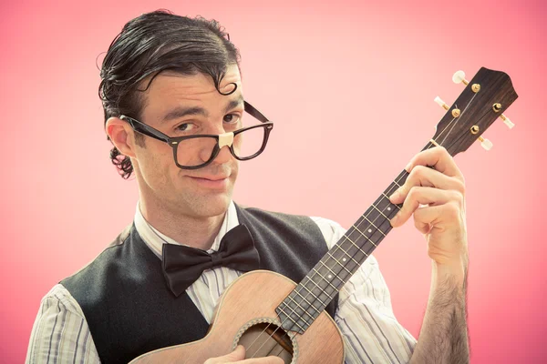 Happy nerd man with glasses play music with ukulele guitar