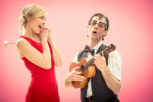 Nerd man boyfriend get woman he love by cupid arrow and play song with ukulele guitar for valentine day