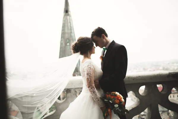 Beautiful wedding couple newlyweds standing on balcony with a view of the city