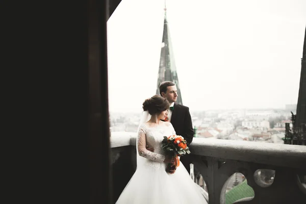 Beautiful wedding couple newlyweds standing on balcony with a view of the city