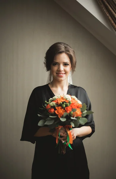 Luxury bride in black robe posing while preparing for the wedding ceremony