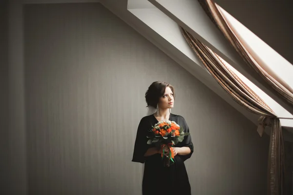 Luxury bride in black robe posing while preparing for the wedding ceremony