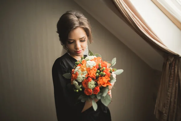 Luxury bride in black robe posing while preparing for the wedding ceremony