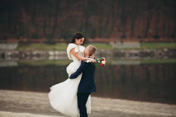 Love and passion - kiss of married young wedding couple near lake