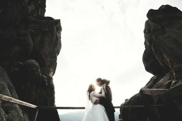 Wedding couple in love kissing and hugging near rocks on beautiful landscape