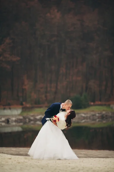 Love and passion - kiss of married young wedding couple near lake