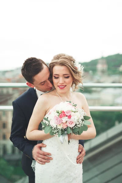 Beautiful couple, bride and groom posing on balcony with backgrounf of old city