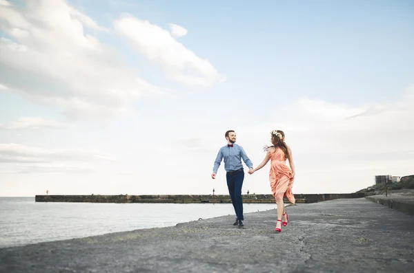 Beautiful loving couple, pride with long dress walking on pier
