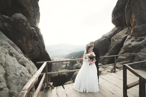 Wedding couple in love kissing and hugging near rocks on beautiful landscape