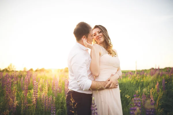 Young wedding couple walking on field with flowers