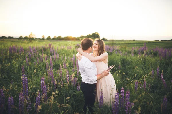 Young wedding couple walking on field with flowers