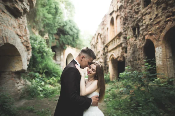 Beautiful fairytale newlywed couple hugging near old medieval castle