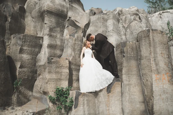 Wedding couple in love kissing and hugging near rocks on beautiful landscape