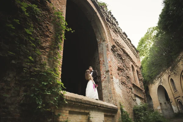 Just married poses and kissing with an old fortress on the background