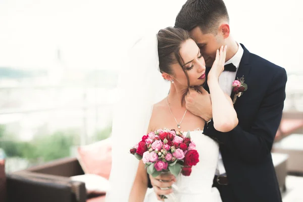 Beautiful couple, bride and groom posing on balcony with backgrounf of old city