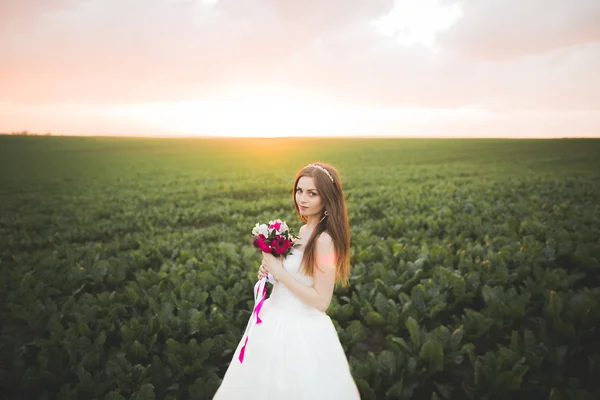 Closeup portrait of beautiful bride with wedding bouquet isolated at green natural summer field background