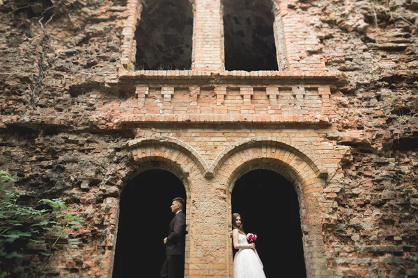 Just married poses and kissing with an old fortress on the background