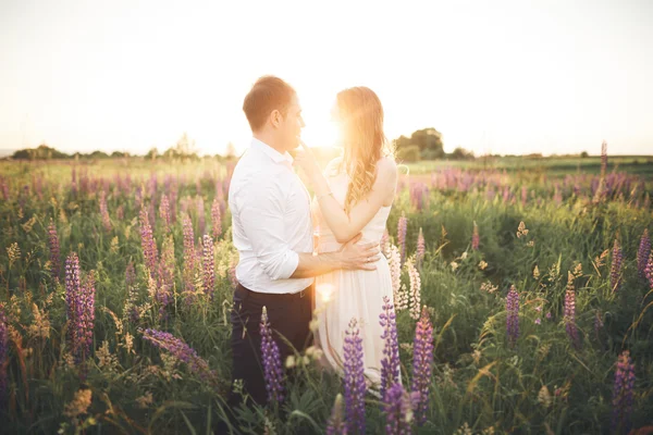 Young wedding couple walking on field with flowers