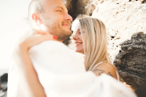 Young models couple posing on the beach with stones