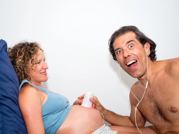 Funny and tender scene of dad listening happily her pregnant wif