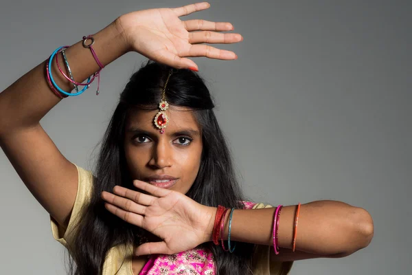 Beautiful and enigmatic young indian woman framing her face with