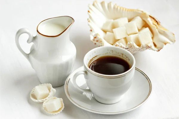 Cup of black coffee with milk and sugar on white background