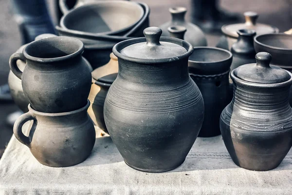 Group of traditional handmade pottery for sale at the market. Ukrainian handmade earthenware utensil. Souvenirs From Ukraine in ethnic style. Black jugs and cups on the table.