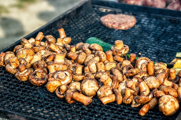 Champignon white mushrooms grilled on grill or BBQ steam and small drops of water. Cooking mushrooms on the grill. Portobello mushrooms marinated and grilling. Grilled vegetables on a grill close up.