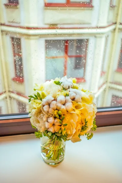 Gentle peony and cotton bouqet on the rainy window