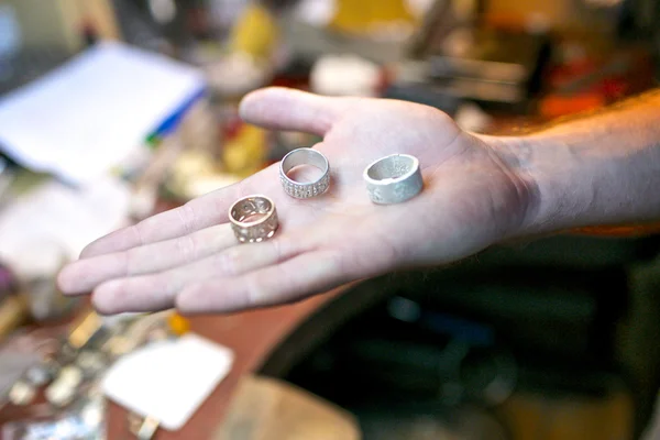 Handmade rings in man hand at jewelry workshop
