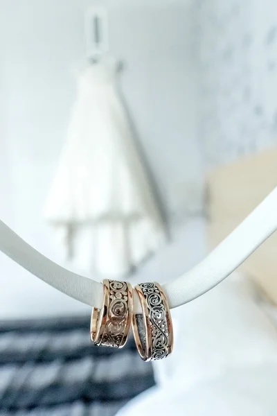 Two rings with rare design in front of wedding dress