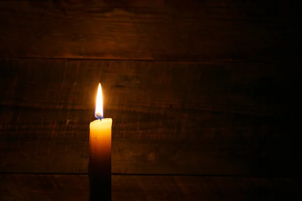 Beeswax candle on old wooden background