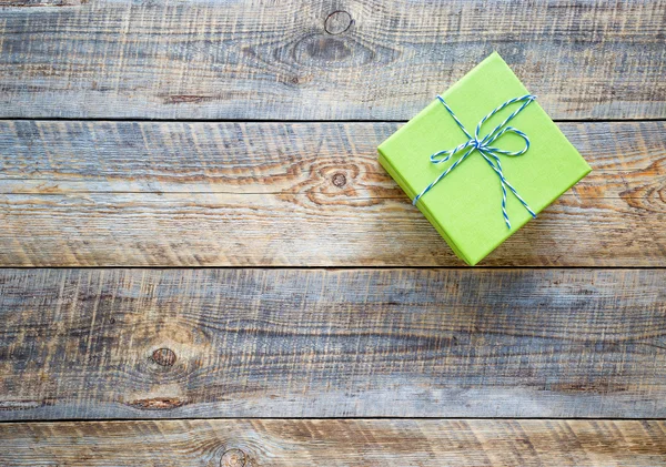 Small green gift box on empty wooden table