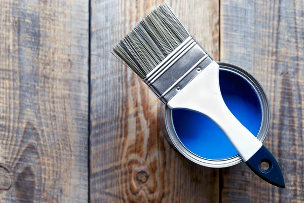 Painting at home with can blue paint on wooden background