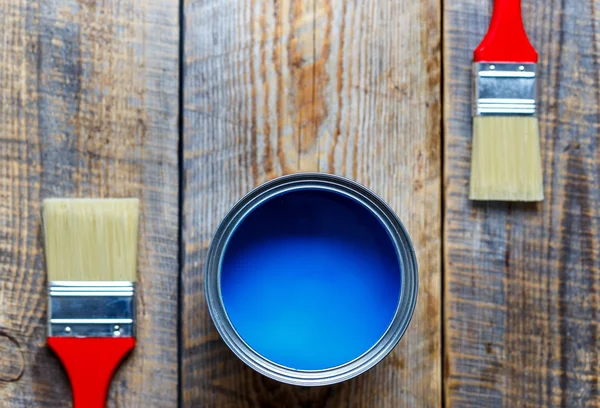 Painting at home with can blue paint on wooden background