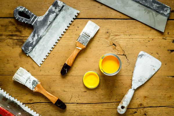 Tools for painting on a wooden table with yellow paint
