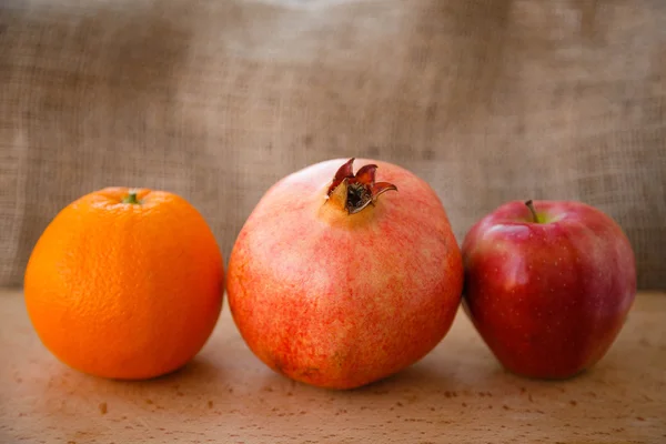 Healthy lifestyle. Healthy food. Proper nutrition. Fruit plate. Useful vitamins food. Apple, orange and pomegranate on a wooden table on light brown background