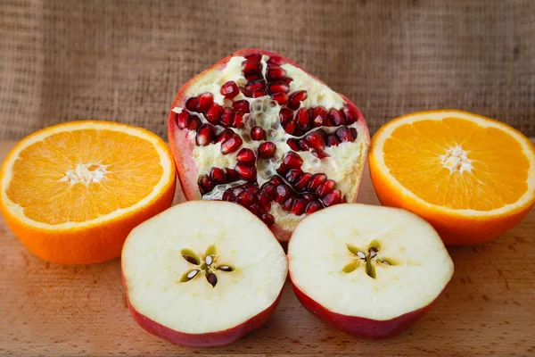 Healthy lifestyle. Healthy food. Proper nutrition. Fruit plate. Useful vitamins food. Apple, orange and pomegranate sliced on a wooden table on light brown background